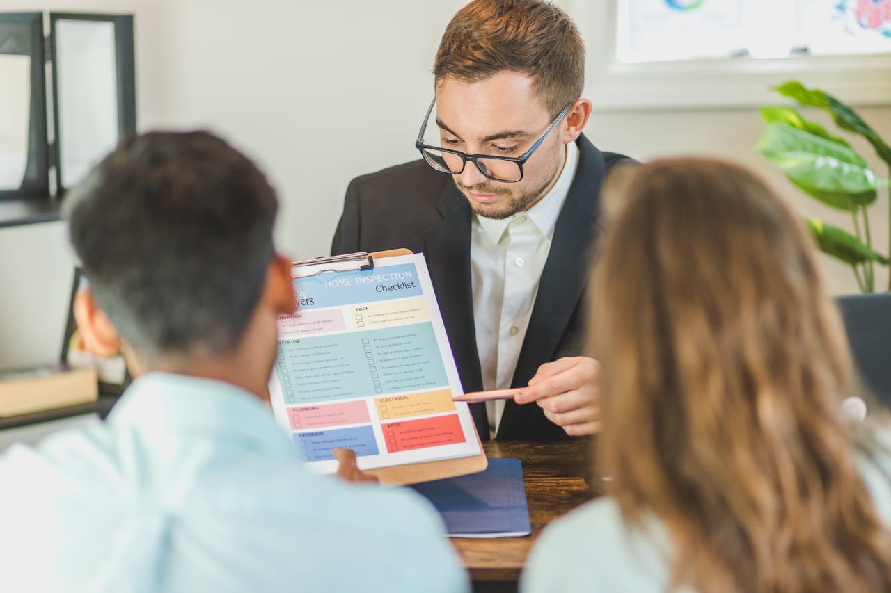 Real estate agent explaining home inspection checklist to clients in an office setting.